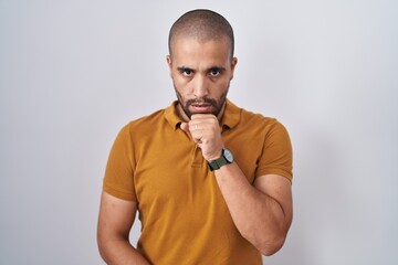 Hispanic man with beard standing over white background feeling unwell and coughing as symptom for cold or bronchitis. health care concept.