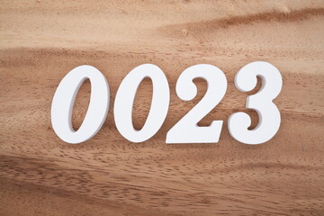 White number 0023 on a brown and light brown wooden background.