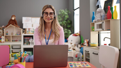 Young blonde woman teacher using laptop working at kindergarten