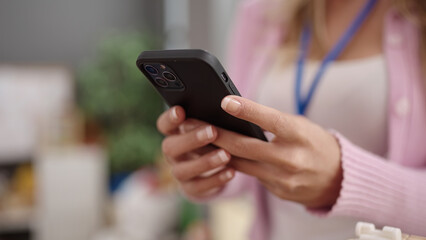 Young blonde woman teacher using smartphone at kindergarten