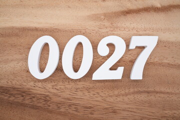 White number 0027 on a brown and light brown wooden background.