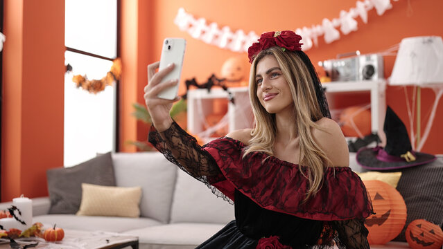 Young blonde woman making selfie by smartphone having halloween party at home