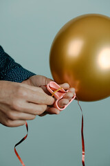 man ties a golden balloon to a red ribbon