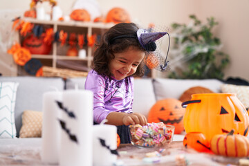 Fototapeta premium Adorable hispanic toddler having halloween party holding sweets at home