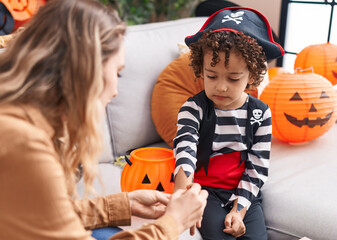Fototapeta premium Woman and toddler having halloween party sitting on sofa at home