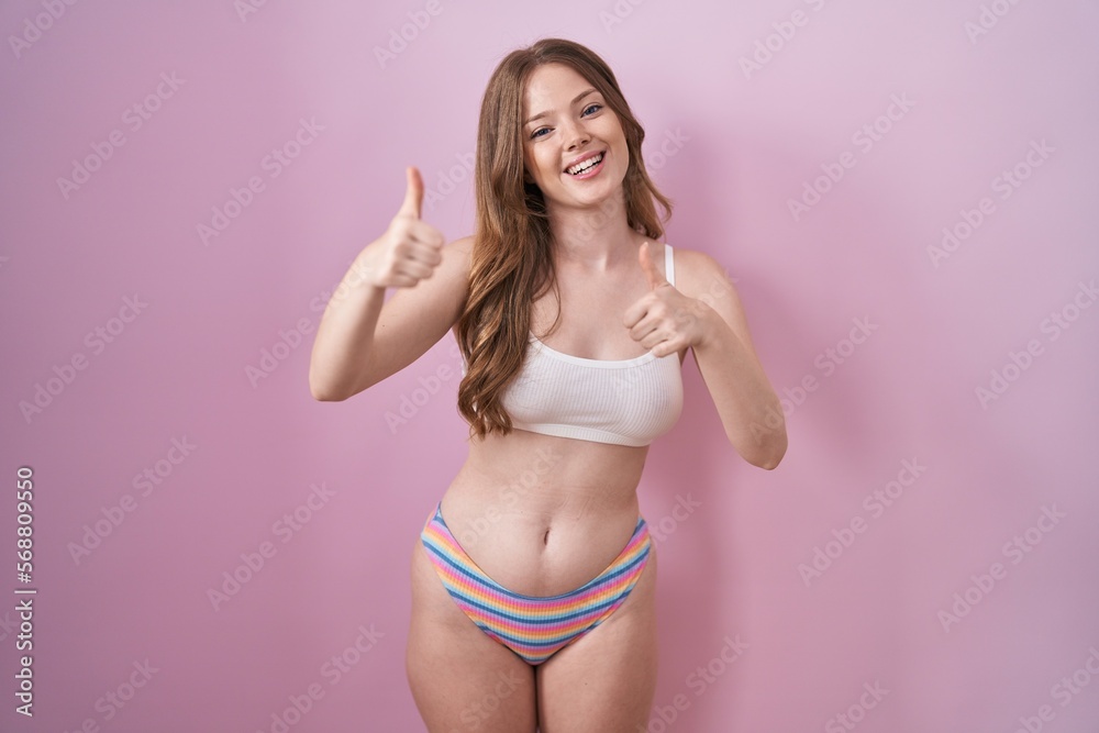 Poster caucasian woman wearing lingerie over pink background approving doing positive gesture with hand, th