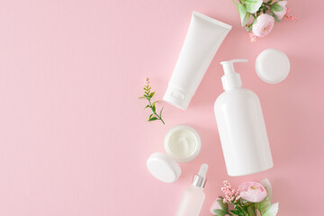 Obraz na płótnie Canvas Organic beauty products concept. Top view composition made of cosmetic tubes without label, dropper bottle and spring flowers on pastel pink background with empty space. Cosmetic mockup.