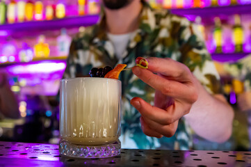 man hand bartender decorated white cocktail in glass on the bar counter