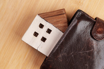 Model of a wooden house in a leather wallet close up