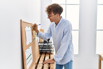 Young caucasian man writing on corkboard working at office