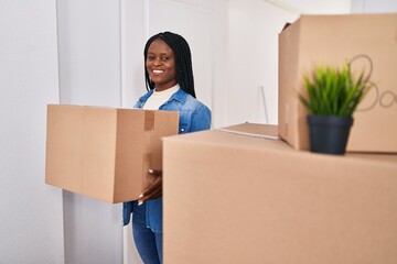 African american woman smiling confident holding package at new home