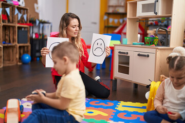 Teacher with boy and girl sitting on table having emotion therapy at kindergarten