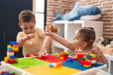 Fototapeta premium Two kids playing with construction blocks sitting on table at kindergarten