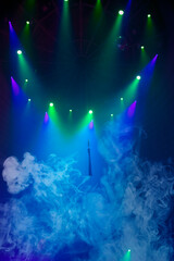 Blue stage circus smoke and green beams from projectors on a blue vertical background.