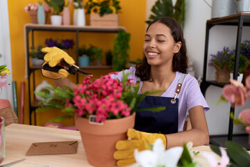 Fototapeta na wymiar Young african american woman florist cutting plants at flower shop