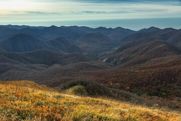 Sunlight over rocky mountain peaks and ridges at dawn. The mountain range of the Caucasus against the background of clouds. Beautiful mountain landscape. 