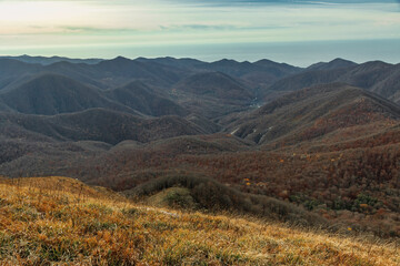 Sunlight over rocky mountain peaks and ridges at dawn. Beautiful mountain landscape. The mountain range of the Caucasus against the background of clouds.