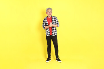 The 40s adult Asian man with casual dressed standing on the yellow background.