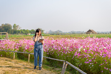 Happy woman farmer owner holding tablet and smartphone at flower farm for modern farming, technology,smart woman, flower business idea concept.