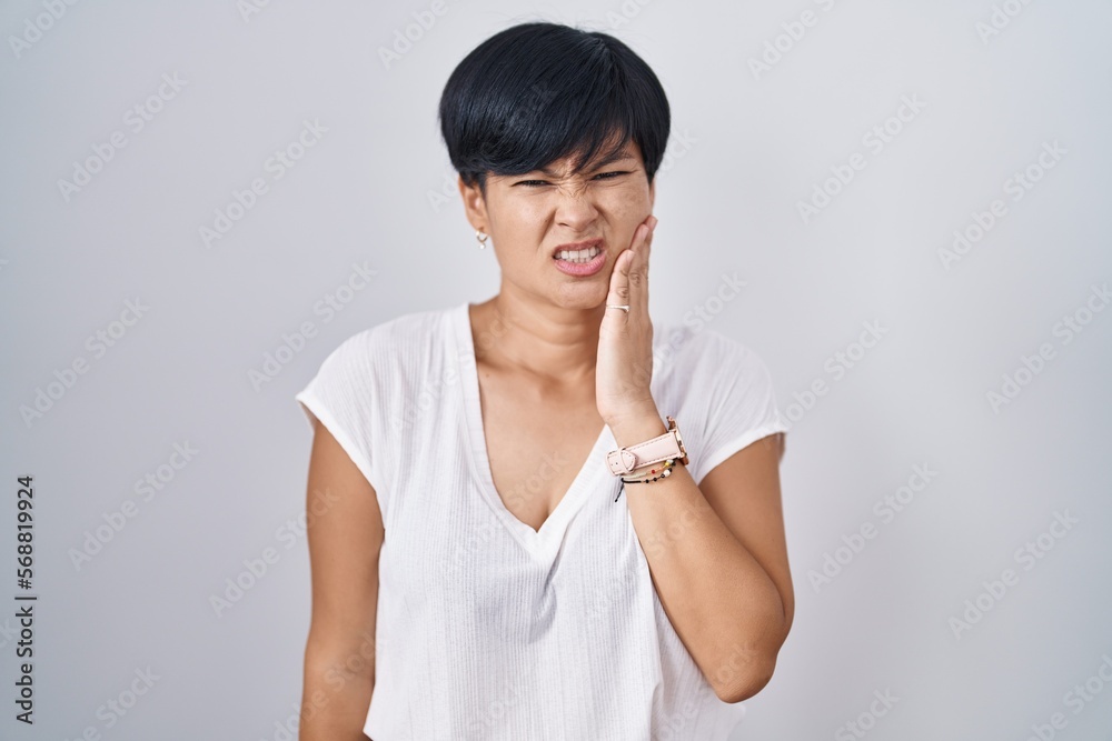 Canvas Prints Young asian woman with short hair standing over isolated background touching mouth with hand with painful expression because of toothache or dental illness on teeth. dentist