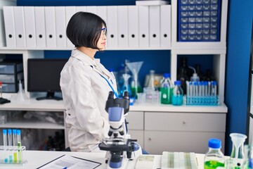 Young asian woman working at scientist laboratory looking to side, relax profile pose with natural face with confident smile.