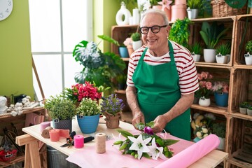 Middle age grey-haired man florist make bouquet of flowers at flower shop