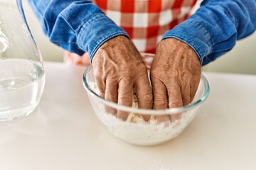 Senior man cooking dough at kitchen