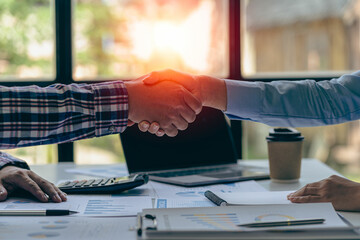 Young businessman and businesswoman in investment agreement, two colleague handshake concept. The deal was achieved by mutual funding after a meeting in the financial bureau.