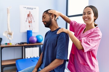 Man and woman wearing physiotherapist uniform having rehab session stretching neck at physiotherpy...