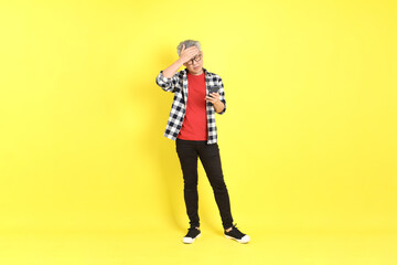 The 40s adult Asian man with casual dressed standing on the yellow background.