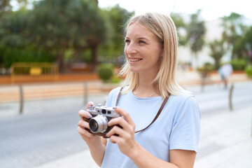 Young blonde woman tourist using vintage camera at street