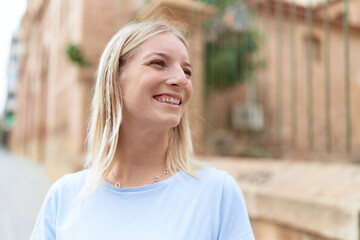 Young blonde woman smiling confident looking to the side at street