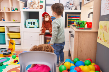 Adorable hispanic boy standing on back view at kindergarten
