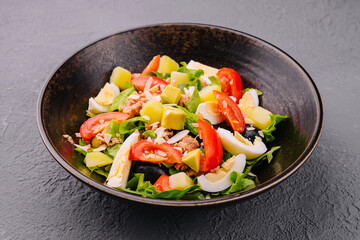 Tuna fish salad with eggs, lettuce, cherry tomatoes, avocado and olives