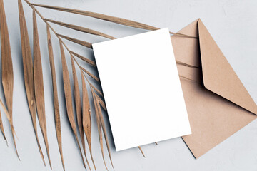 Blank invitation or greeting card mockup with palm tree leaf and envelope