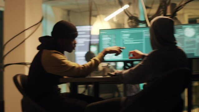 Team of hackers planning hacktivism and cryptojacking at night, using dark web for illegal activity. People using encryption or virus to steal data and crash government system. Handheld shot.