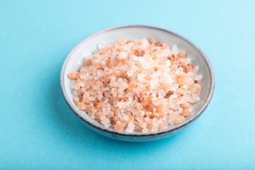 plate with pink Himalayan salt on blue pastel. side view, close up.