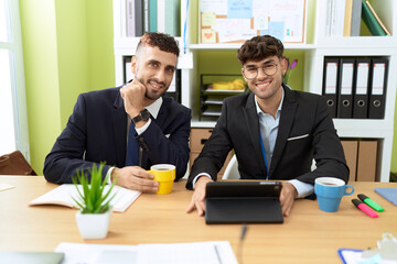 Two hispanic men business workers using touchpad working at office
