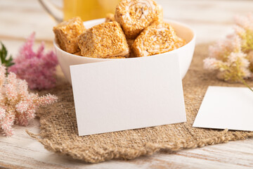 White business card with traditional turkish delight (rahat lokum) on a white wooden background. side view, close up.