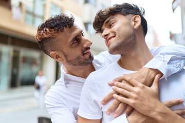 Two hispanic men couple smiling confident hugging each other at street