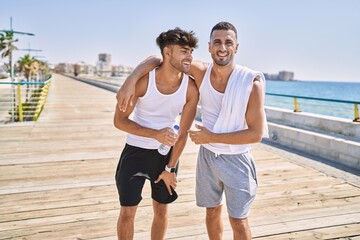 Two hispanic men sporty couple smiling confident and hugging each other standing at seaside