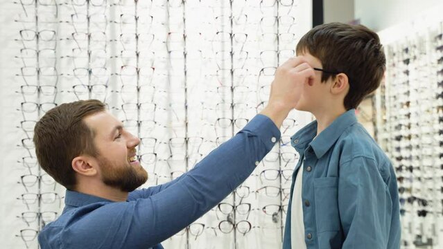 Little boy in optics store choosing glasses with his father. Ophthalmology concept
