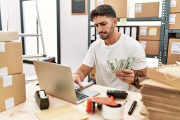 Handsome hispanic man working doing countability at e-commerce store