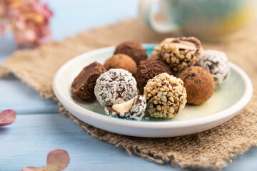 Chocolate truffle candies with cup of coffee on a blue wooden background. side view, close up, selective focus.