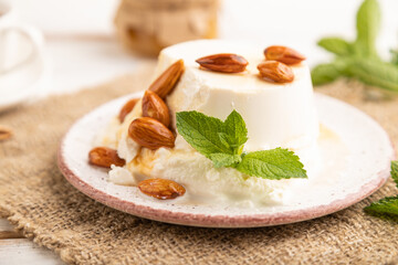 Ricotta cheese with honey and almonds on white wooden. side view, selective focus.