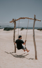 Mann schaukelt in einer Dünenlandschaft. Die Dunas do Siriú Garopaba. Dünen direkt am Meer. Dünen aus Sand. 3