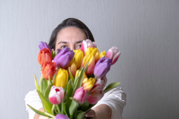 A beautiful young woman without makeup holds a bouquet of tulips. The concept of natural beauty.