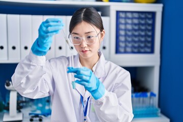 Chinese woman scientist pouring liquid on test tube at laboratory