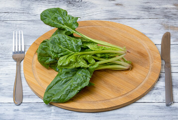 Spinach leaves on a wooden plate on a wooden table. The concept of healthy food.