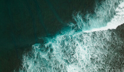 Fototapeta na wymiar top drone view of a beach with big waves breaking on a cliff of a remote coast line